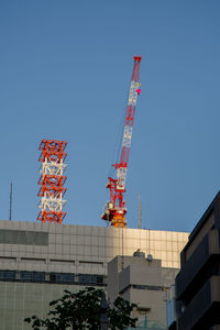 Low angle view of crane against clear blue sky