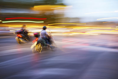 Blurred motion of people riding motorcycle on road