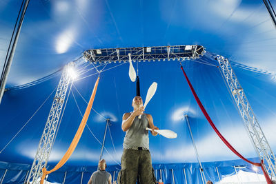 Male athlete with juggling pins practicing at circus