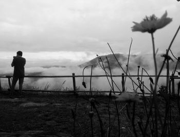 Rear view of man standing on field against sky