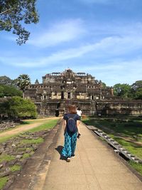 Rear view of woman with arms outstretched against sky