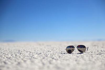Close-up of sunglasses on beach against sky