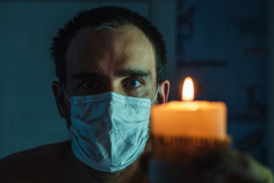 A close-up of the face of a white man wearing a medical mask against the background