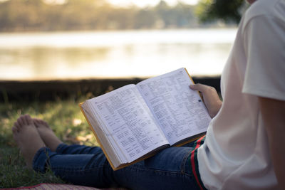 Low section of woman reading book at park