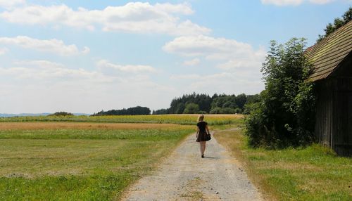 Rear view of woman walking on field