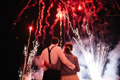 Rear view of people watching firework display at night