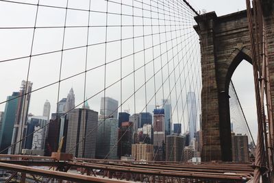 View of suspension bridge in city against sky