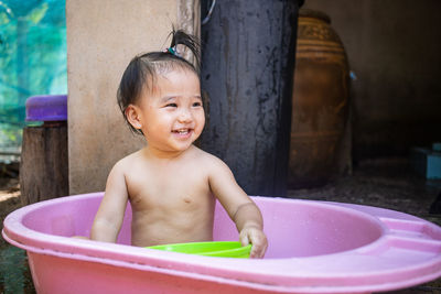 Portrait of shirtless boy sitting in bathroom