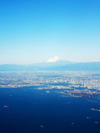 Aerial view of city by sea against clear blue sky