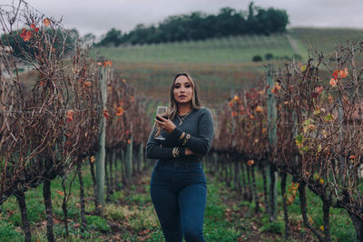 Young woman using phone while standing on field