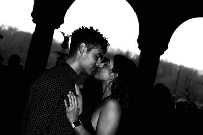 Young couple kissing against sky