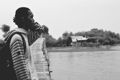 Side view of man standing by lake against sky