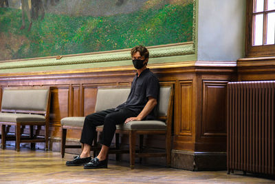 Full length portrait of young man sitting on seat