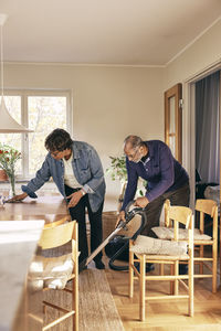 Senior couple helping each other while cleaning home