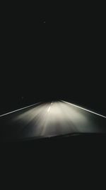 Illuminated road seen through car windshield at night