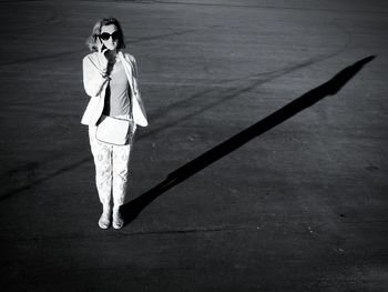 Portrait of woman talking on phone while standing on footpath