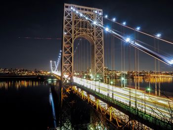 Illuminated bridge over river at night