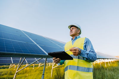 Senior male engineer with digital tablet contemplating in solar field