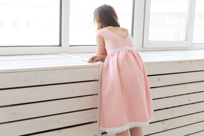 Rear view of woman standing against window