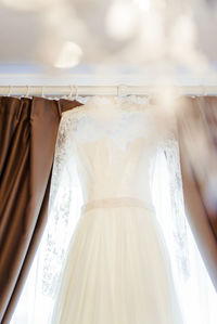 Close-up of wedding dress hanging on window