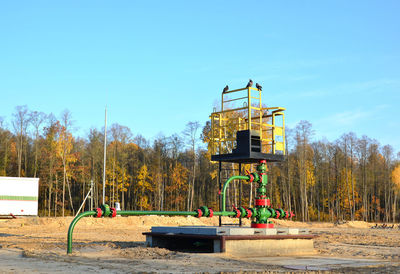 Built structure by trees against clear blue sky