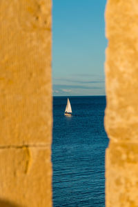 Sailboat on sea against clear blue sky