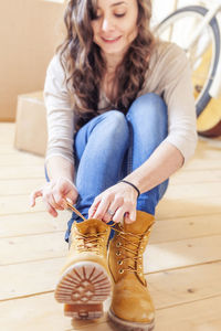 Low section of woman sitting on hardwood floor