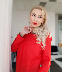 Portrait of beautiful young woman standing against red wall