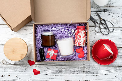 Seasonal gift box for valentine day with candle, red cup and heart shape sweets. 