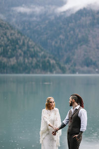 A happy couple in love and married embrace in nature by the lake and the misty mountains