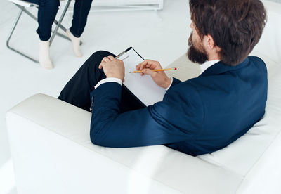 High angle view of businessman writing on clipboard