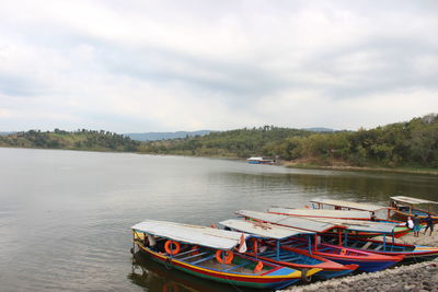 Boats moored on lake against sky