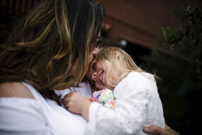 Close-up of happy mother carrying daughter while standing at tourist resort