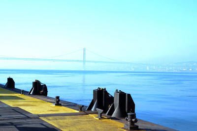 Bridge over sea against clear blue sky