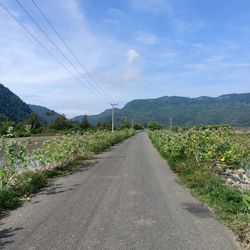 Road amidst field against sky