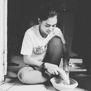 Woman cutting corn while sitting on floor at home