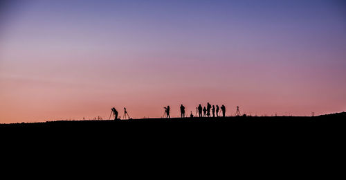 Silhouette people on landscape at sunset