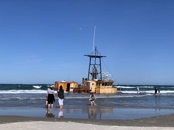 People on beach by sea against sky