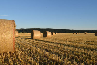 Hay bales on field against clear sky