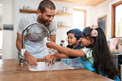 Father washing hands with son and daughter. family learning about hand hygiene and cleaning habits