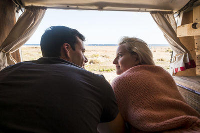 Rear view of couple lying in camper trailer