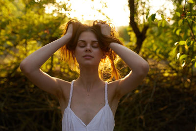 Portrait of young woman standing against plants