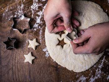 Cropped hands cutting dough with heart shape cutter at home