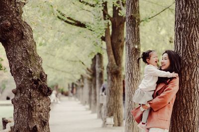 Woman standing by tree trunk