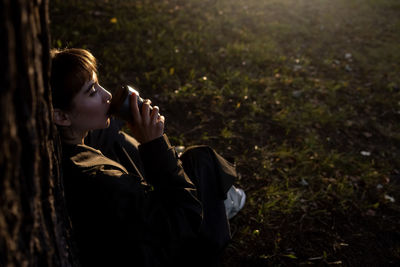 Side view of young woman sitting on field