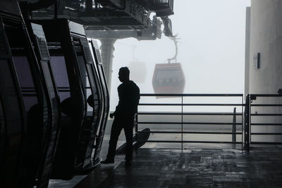 Rear view of silhouette man walking on bridge