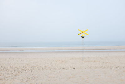 Warning sign at beach against clear sky