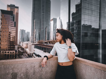 Young woman looking away against buildings in city