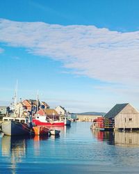 Boats in sea by town against sky