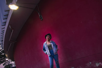 Portrait of young man standing against illuminated wall